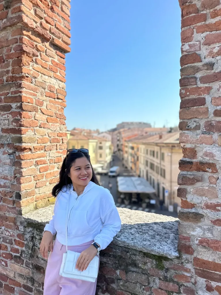 Best views in Verona from Castel San Pietro framed by brick walls with a person overlooking the city