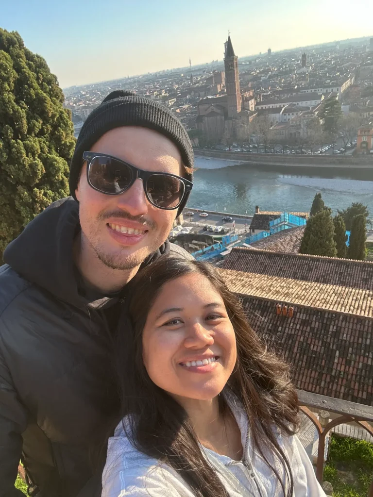 Best Time to Visit Verona view from Castel San Pietro with a couple smiling in the foreground overlooking the Adige River and historic skyline
