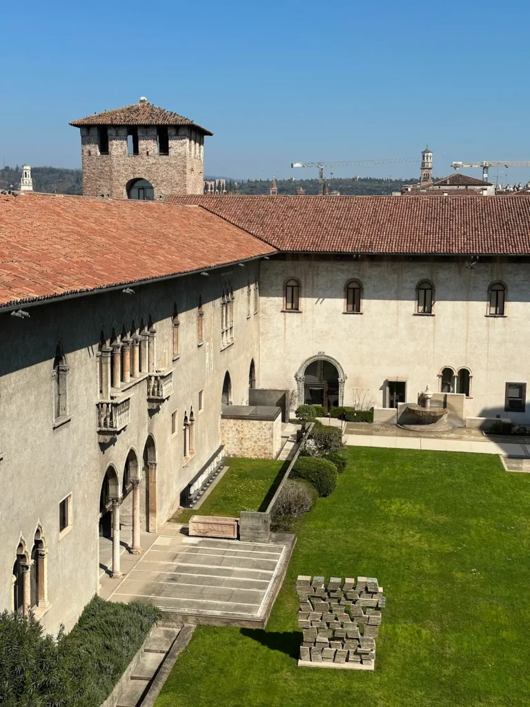 Castelvecchio Verona courtyard with historic buildings, red tiled roofs, and a central green lawn.