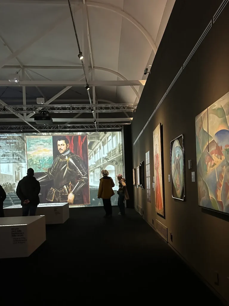 Castelvecchio Museum Verona modern gallery with paintings displayed on dark walls and visitors viewing a large projected portrait.