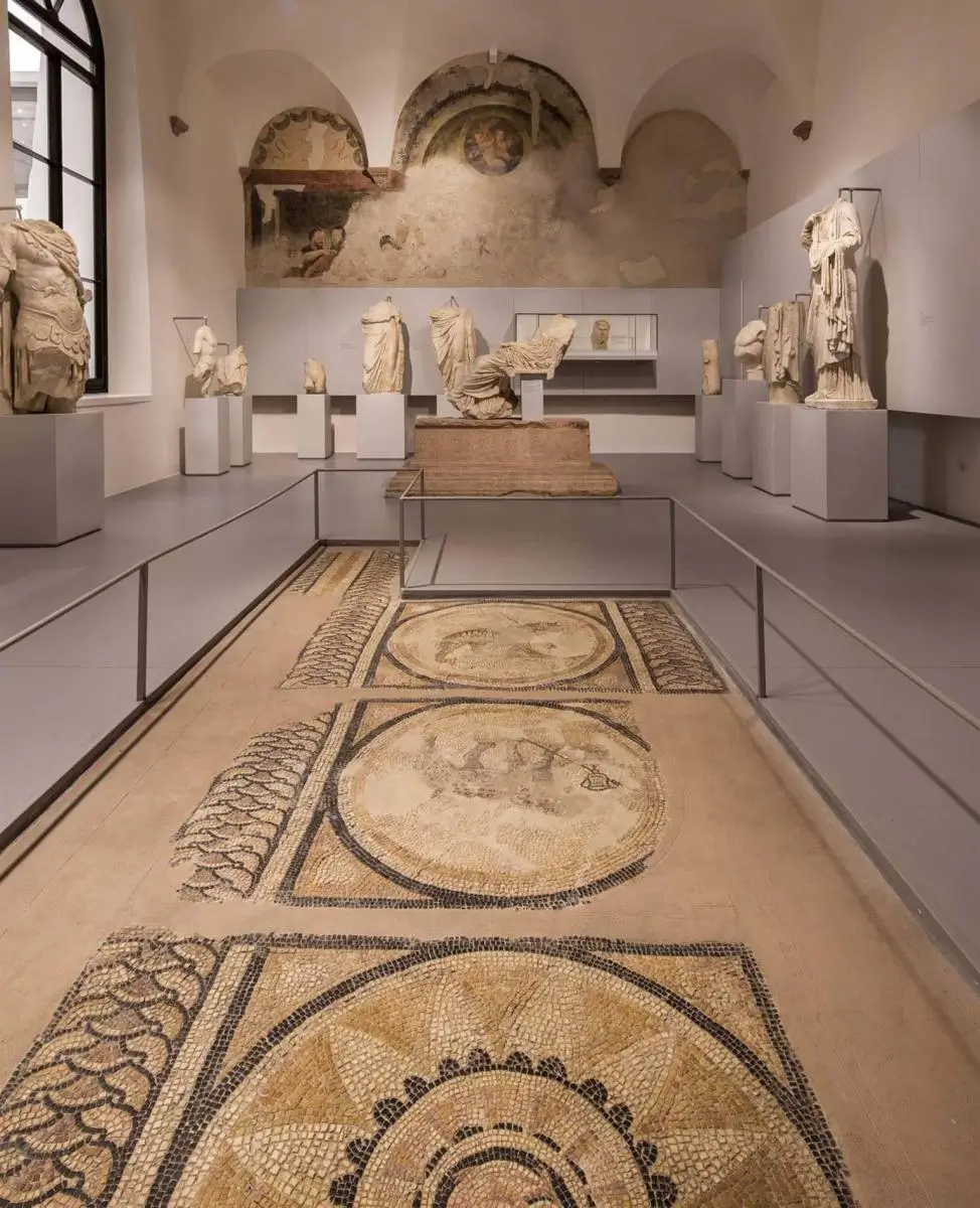 Interior view of the Archaeological Museum at the Roman Theatre in Verona, showcasing a collection of fragmented Roman statues displayed on pedestals.