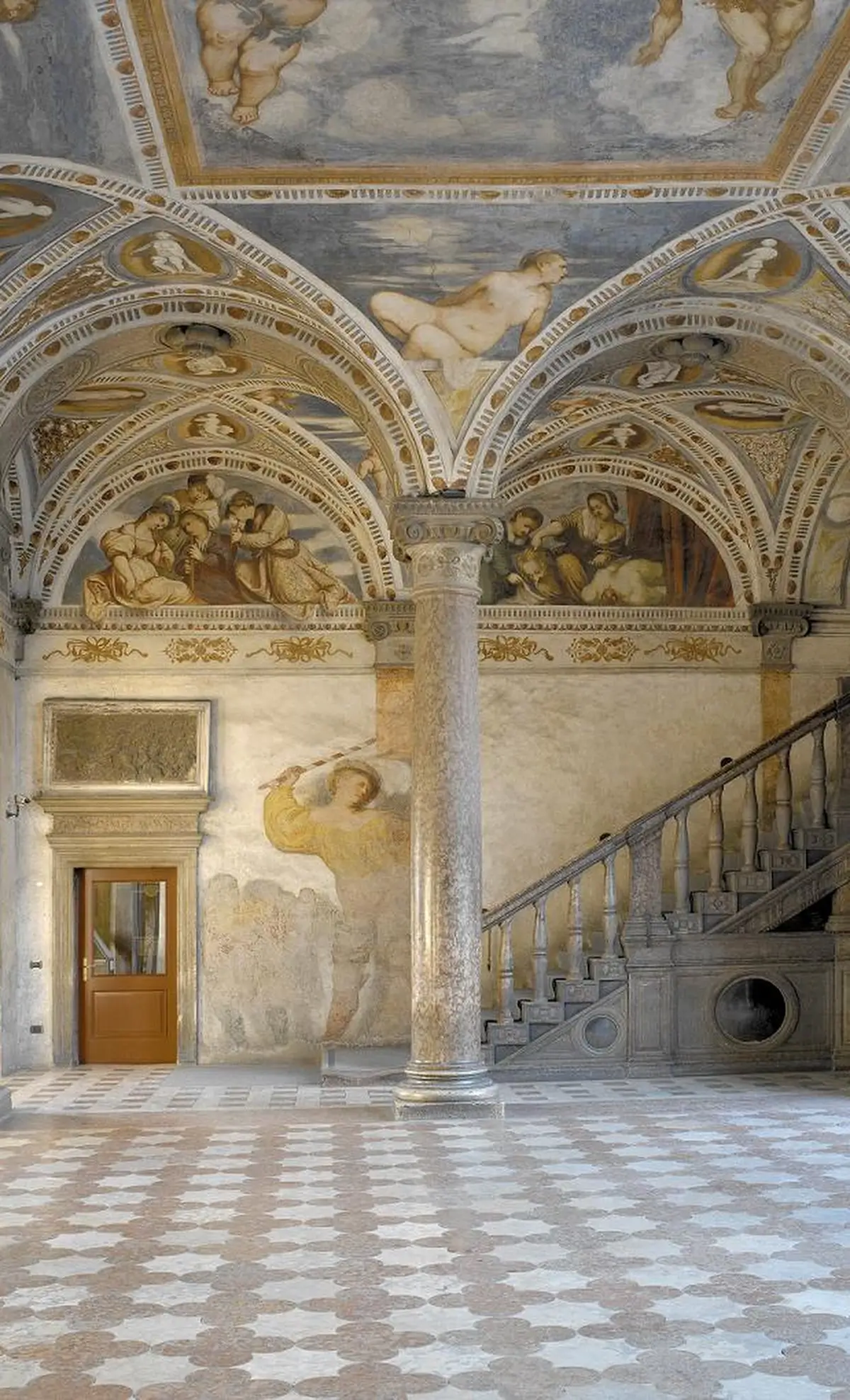 Lavishly decorated interior of Buonconsiglio Castle in Trento, featuring detailed Renaissance frescoes on the vaulted ceiling and walls, including mythological and religious scenes.
