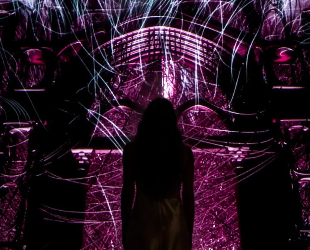 a person silhouetted against a vivid, digital art display inside the Shakespeare Interactive Museum (SIM) in Verona.