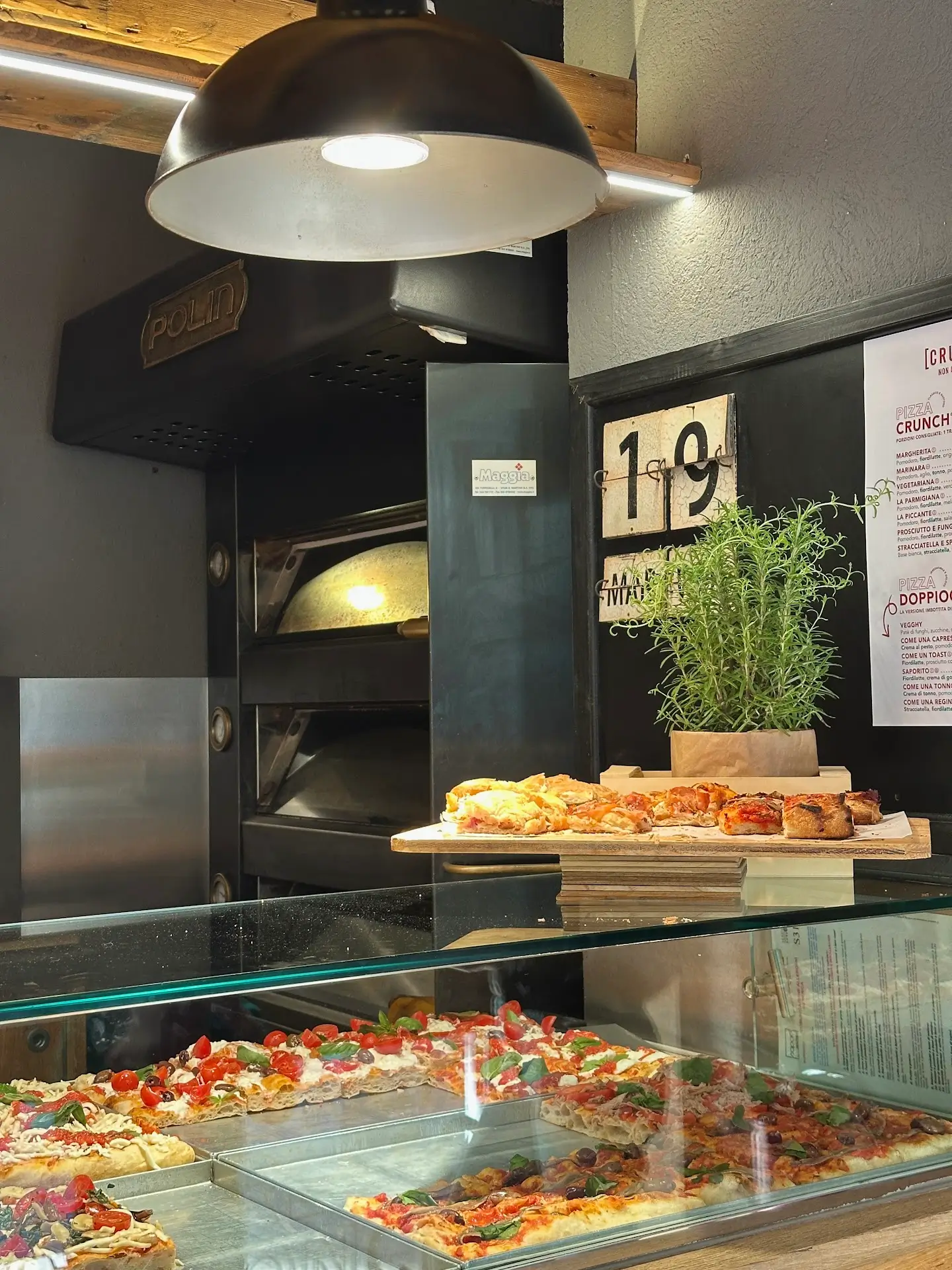 Sheet pizza slices at a Verona pizzeria counter with oven in background – what to eat in Verona street food