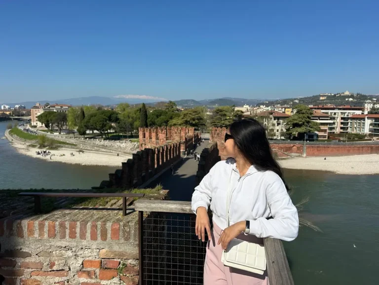 Best views in Verona from Scaliger Bridge with a person overlooking the Adige River and historic brick walls
