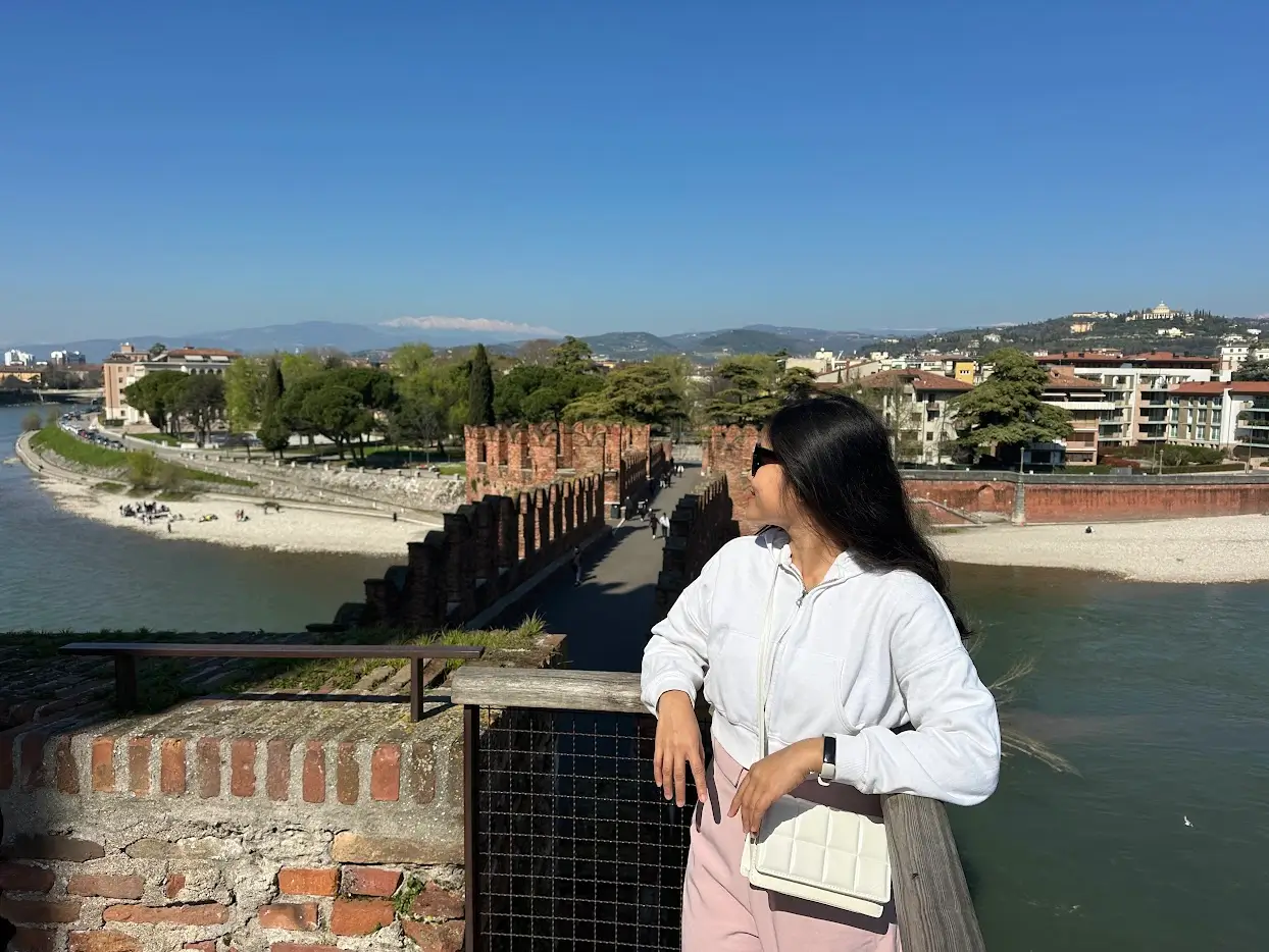 Best views in Verona from Scaliger Bridge with a person overlooking the Adige River and historic brick walls
