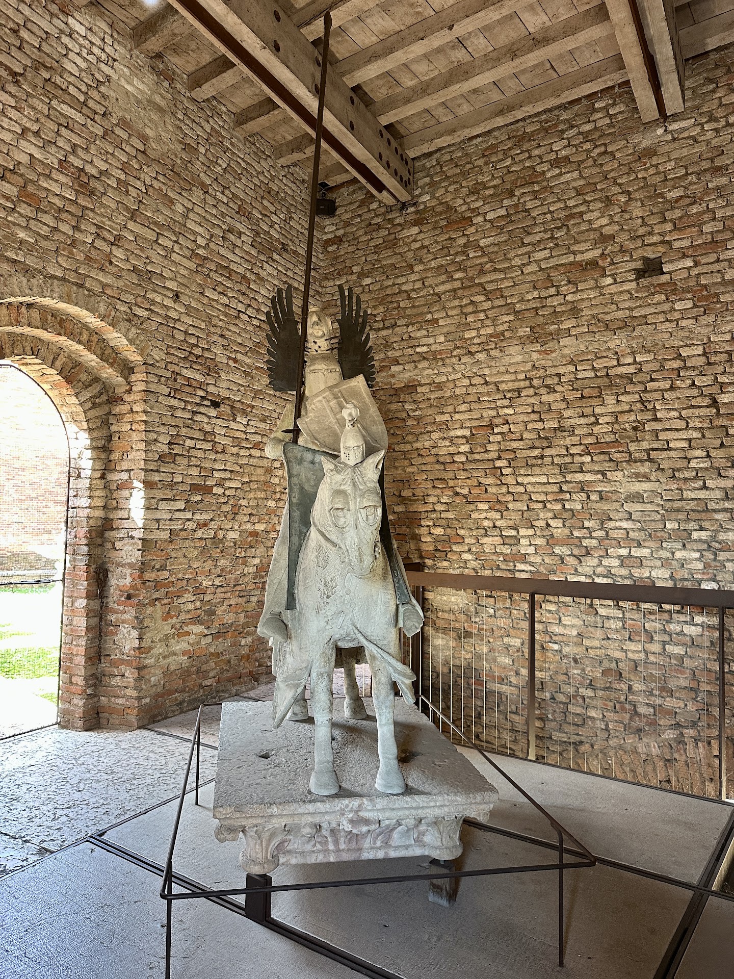 Equestrian statue of Mastino II della Scala displayed inside Castelvecchio Museum in Verona, set against exposed brick walls and elevated on a platform