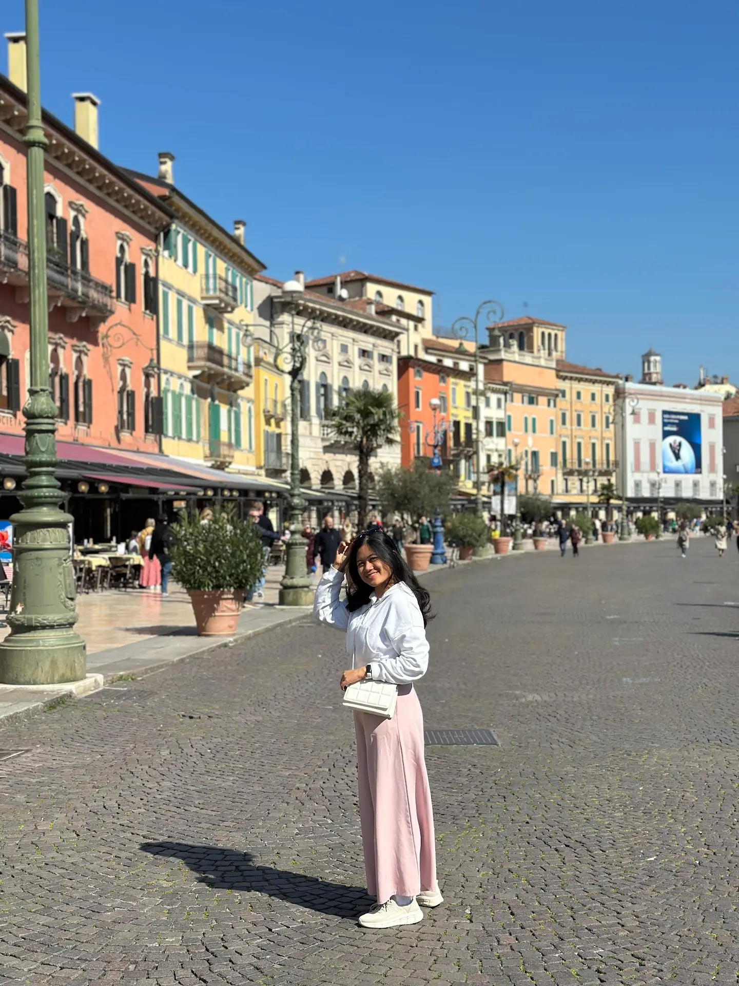 Woman standing in Piazza Bra with colorful buildings and cafés in Verona’s historic centre