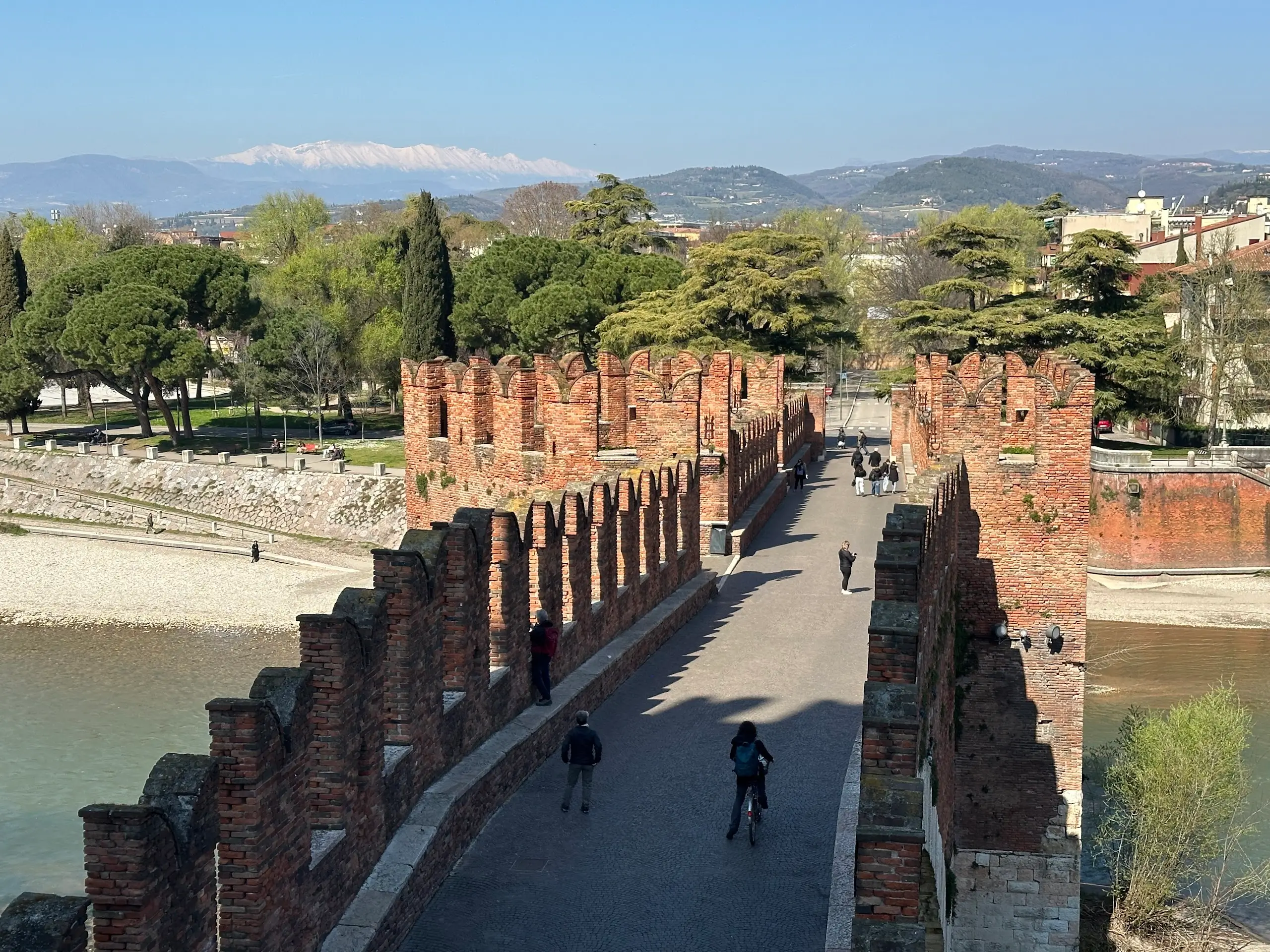 Castelvecchio Verona bridge with red brick crenellated walls over the river and people walking across.