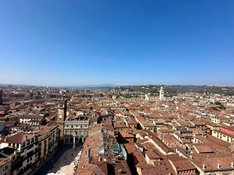 Best Time to Visit Verona panoramic view from Torre dei Lamberti showing terracotta rooftops, historic buildings, and surrounding hills under a clear blue sky