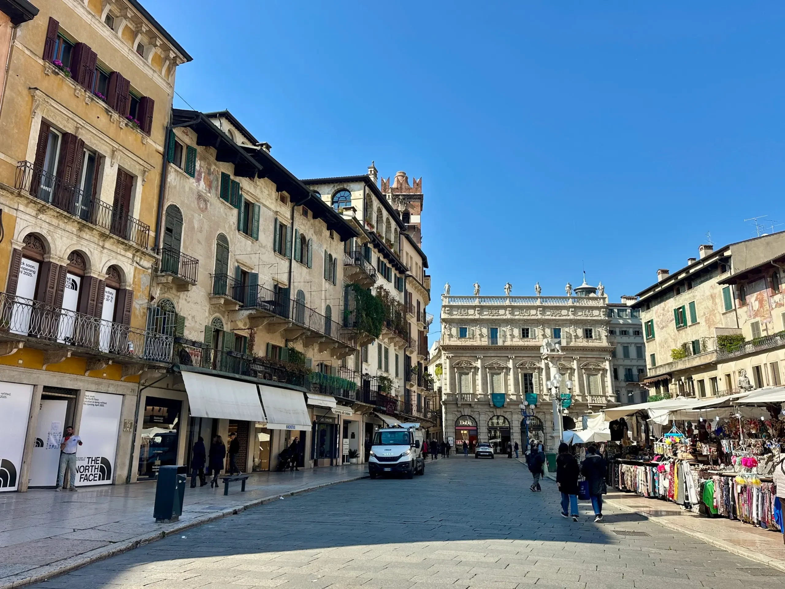 Street view of Piazza delle Erbe with market stalls and historic buildings in Verona
