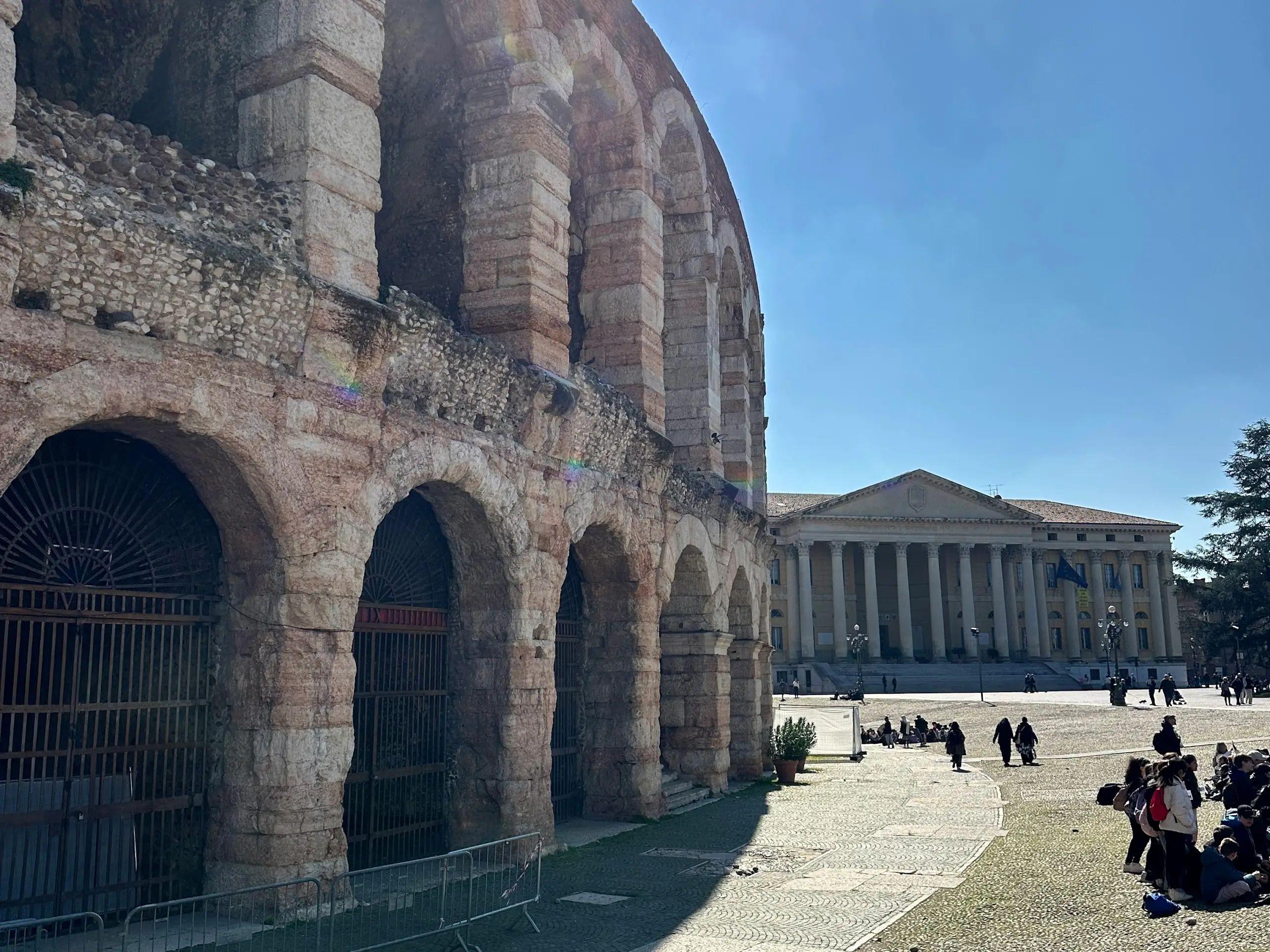 Exterior view of the Arena di Verona with its stone arches, facing Piazza Bra and nearby historic buildings